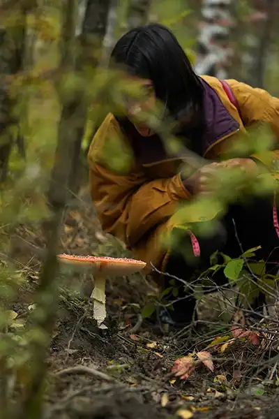 Participant takes a close look at a fly agaric in the forest